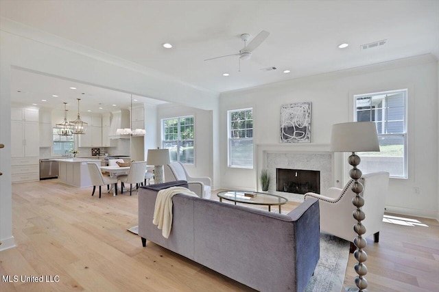 living room featuring light hardwood / wood-style flooring, plenty of natural light, and crown molding