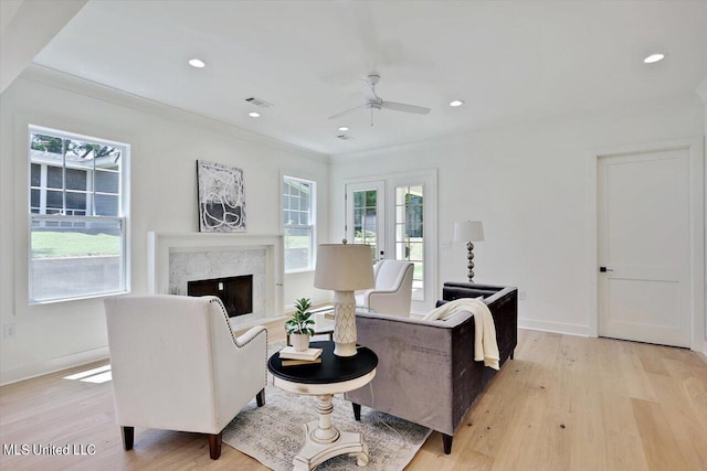 living room featuring light hardwood / wood-style floors, crown molding, ceiling fan, and a wealth of natural light