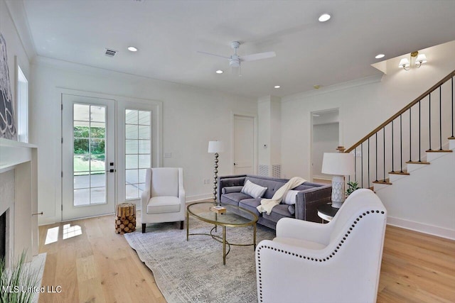 living room featuring ornamental molding, light hardwood / wood-style flooring, french doors, and ceiling fan