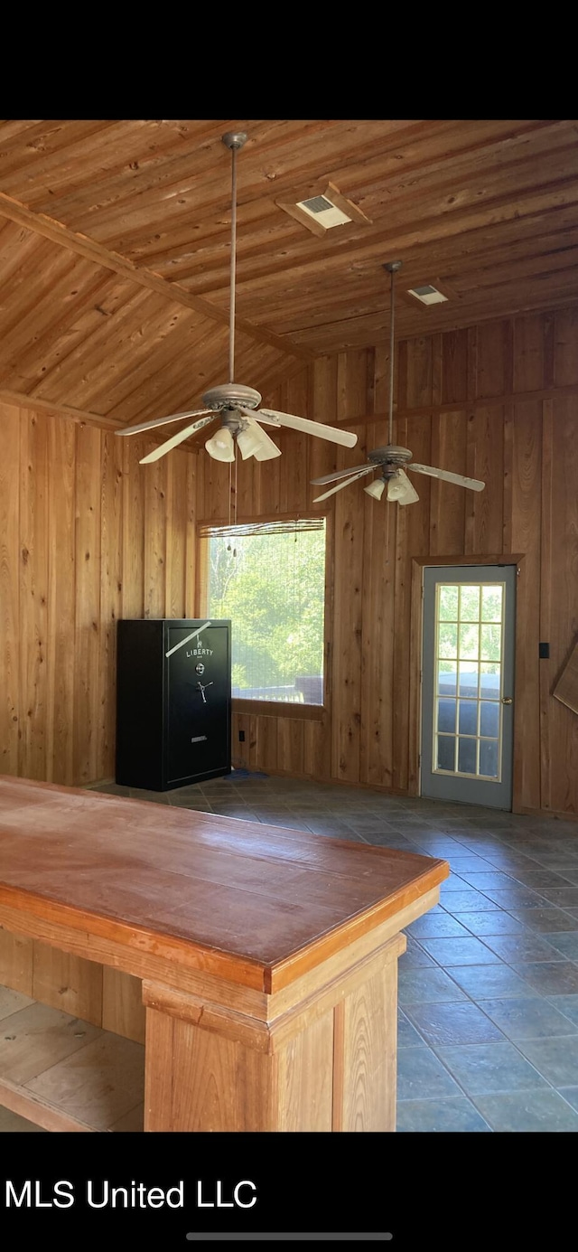 kitchen with wooden walls, vaulted ceiling, wood ceiling, and ceiling fan