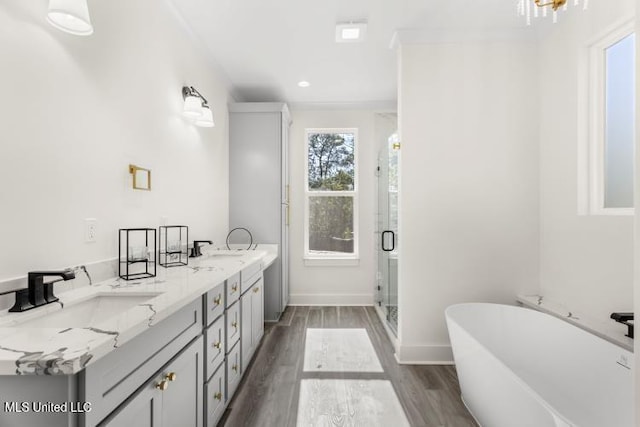 full bath with a freestanding bath, a sink, a shower stall, wood finished floors, and baseboards