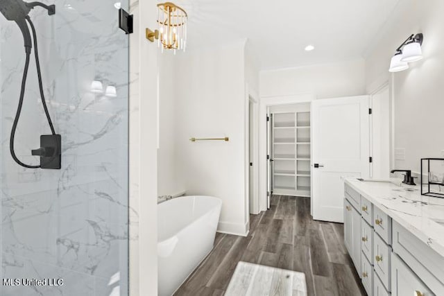 bathroom featuring wood finished floors, a sink, a soaking tub, a marble finish shower, and double vanity