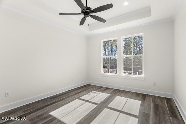 spare room featuring baseboards, a raised ceiling, and dark wood-type flooring