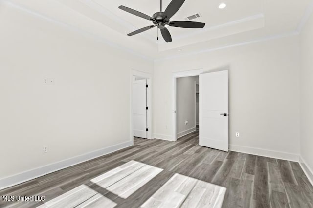 unfurnished bedroom with wood finished floors, recessed lighting, a raised ceiling, and baseboards