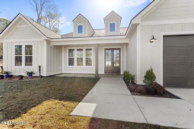 entrance to property featuring a lawn, board and batten siding, and french doors