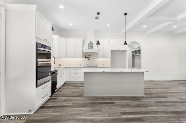 kitchen featuring premium range hood, arched walkways, white cabinets, and beamed ceiling