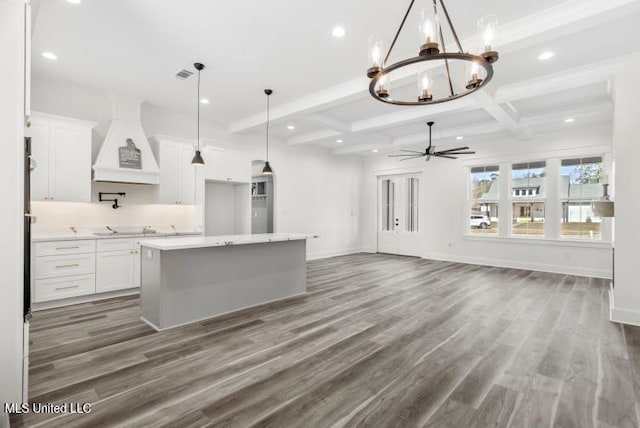 kitchen featuring a center island, white cabinets, custom range hood, and beamed ceiling