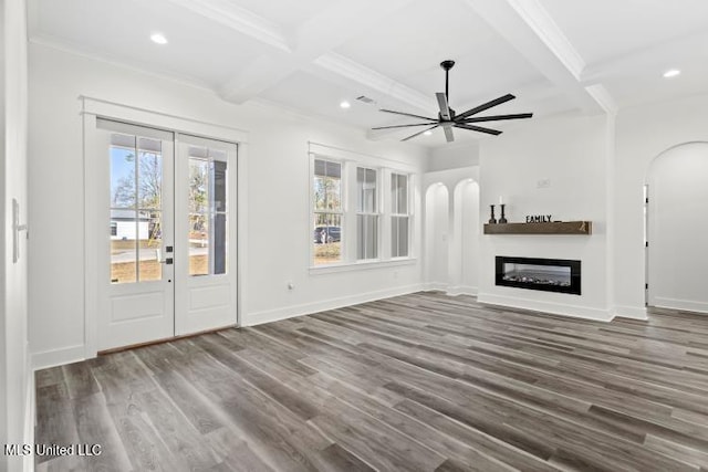 unfurnished living room featuring arched walkways, a glass covered fireplace, a ceiling fan, and wood finished floors