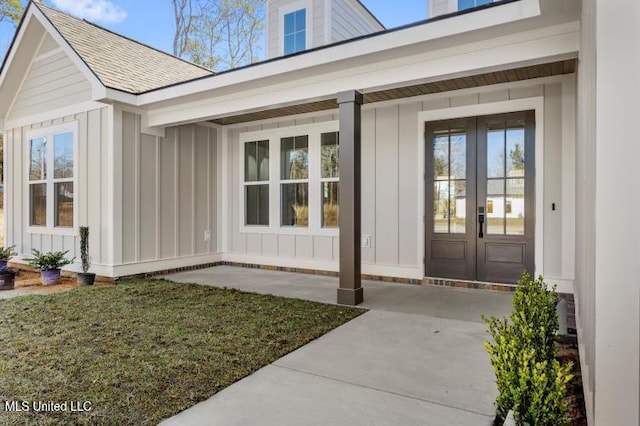 entrance to property featuring board and batten siding, french doors, and roof with shingles