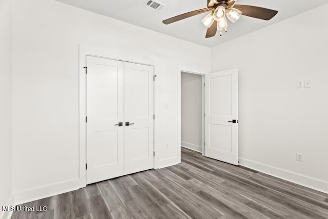 unfurnished bedroom featuring ceiling fan, wood finished floors, visible vents, baseboards, and a closet