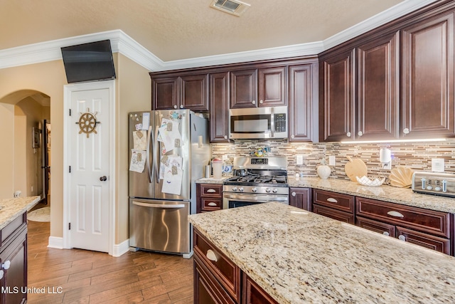 kitchen featuring light stone countertops, appliances with stainless steel finishes, backsplash, crown molding, and hardwood / wood-style flooring