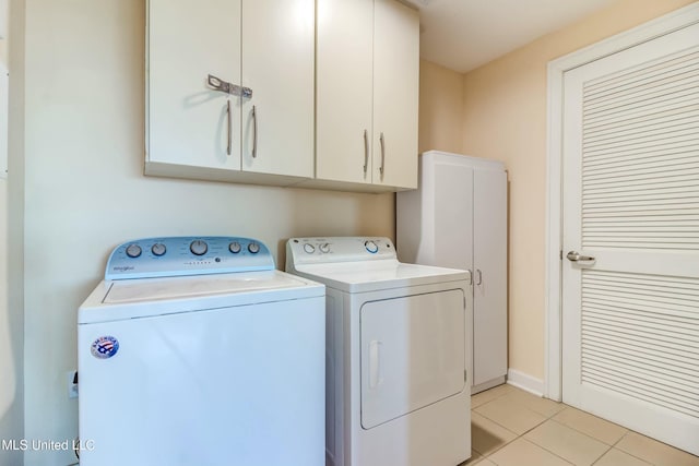 laundry room with light tile patterned floors, washing machine and dryer, and cabinet space