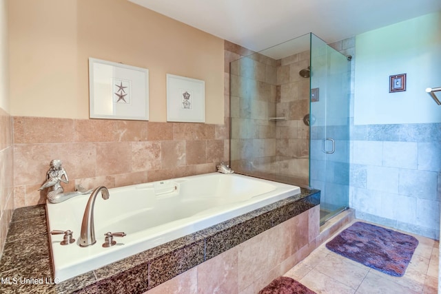 bathroom with a stall shower, a garden tub, tile walls, and tile patterned floors