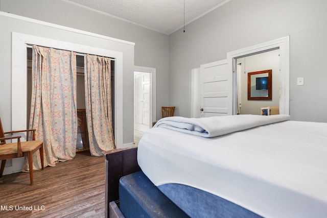 bedroom featuring crown molding, dark wood-type flooring, and a textured ceiling