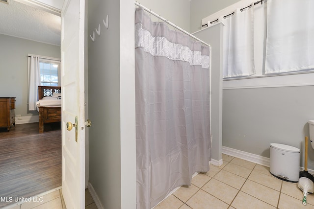 bathroom featuring walk in shower, tile patterned floors, and a textured ceiling