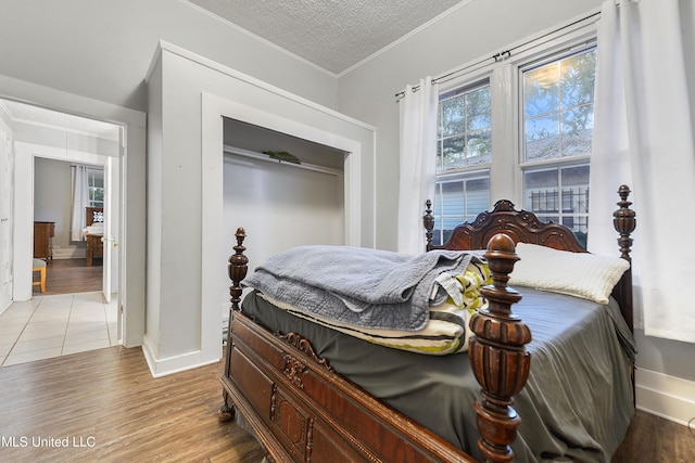 bedroom with hardwood / wood-style flooring, ornamental molding, and a textured ceiling