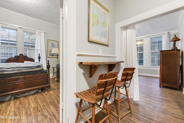 bedroom featuring wood-type flooring, ornamental molding, and a textured ceiling