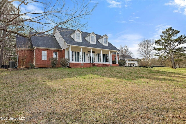 cape cod house featuring roof with shingles, central air condition unit, a front yard, a porch, and brick siding