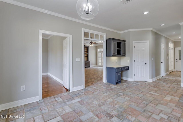 kitchen featuring baseboards, light countertops, stone tile flooring, and ornamental molding