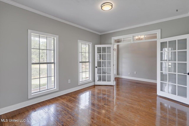 spare room with crown molding, baseboards, wood finished floors, and french doors