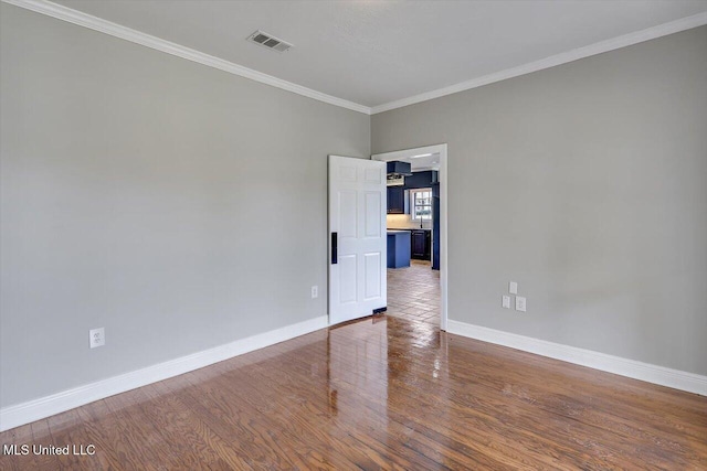 empty room with wood finished floors, visible vents, and baseboards