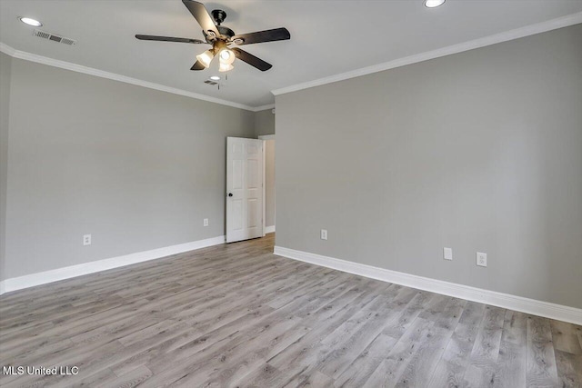 empty room featuring a ceiling fan, visible vents, baseboards, light wood finished floors, and crown molding