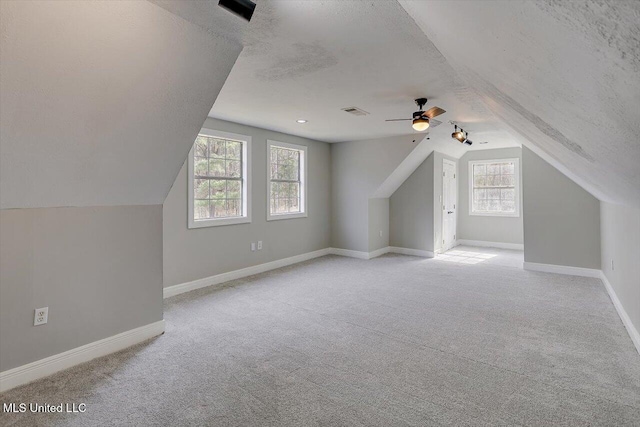 bonus room featuring a textured ceiling, light carpet, and baseboards