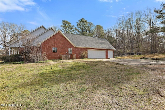 view of home's exterior featuring a garage, driveway, brick siding, and a lawn