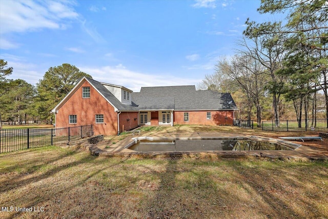 back of house featuring brick siding, a lawn, and fence