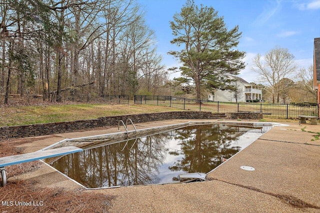 view of pool featuring fence and a diving board