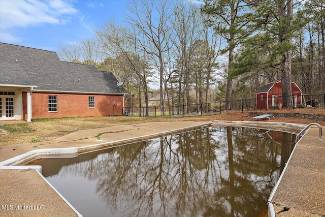 view of swimming pool with an outbuilding, fence, and a barn