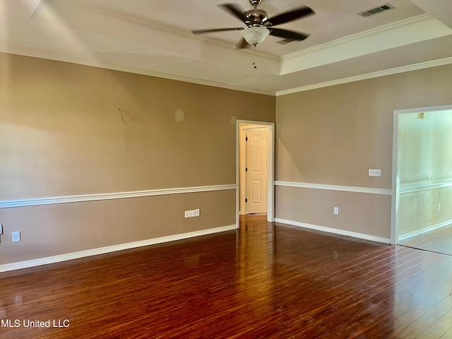 spare room featuring a raised ceiling, dark wood-type flooring, ceiling fan, and crown molding