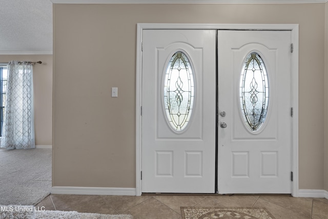 tiled entryway with ornamental molding and a textured ceiling