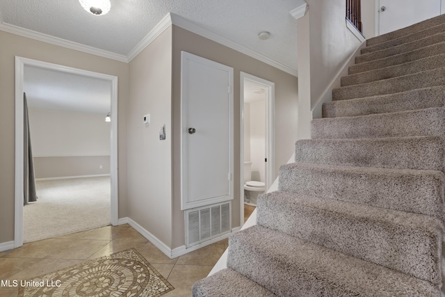 staircase featuring crown molding, tile patterned flooring, and a textured ceiling