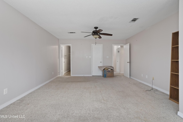 unfurnished bedroom with ceiling fan, light colored carpet, and a textured ceiling