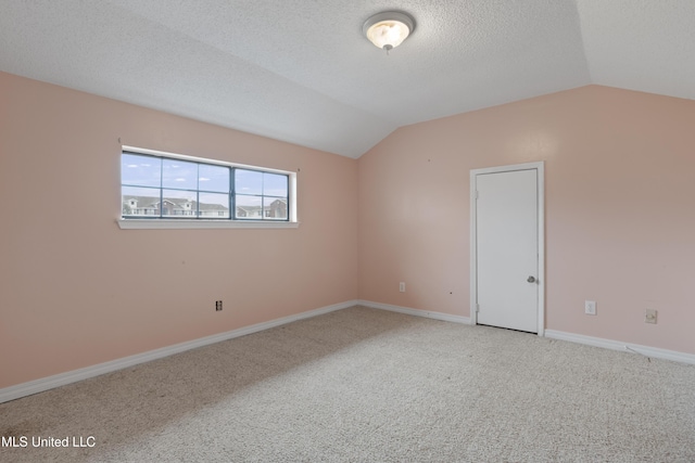 spare room featuring lofted ceiling, a textured ceiling, and carpet flooring