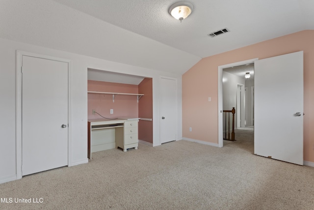 unfurnished bedroom with lofted ceiling, light carpet, and a textured ceiling