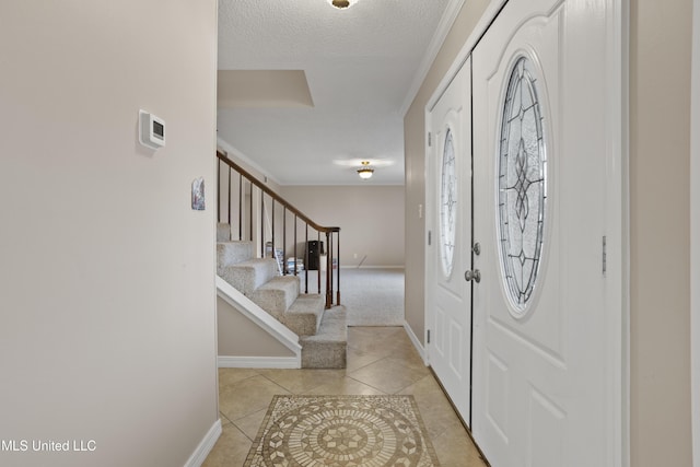 tiled entrance foyer featuring ornamental molding and a textured ceiling