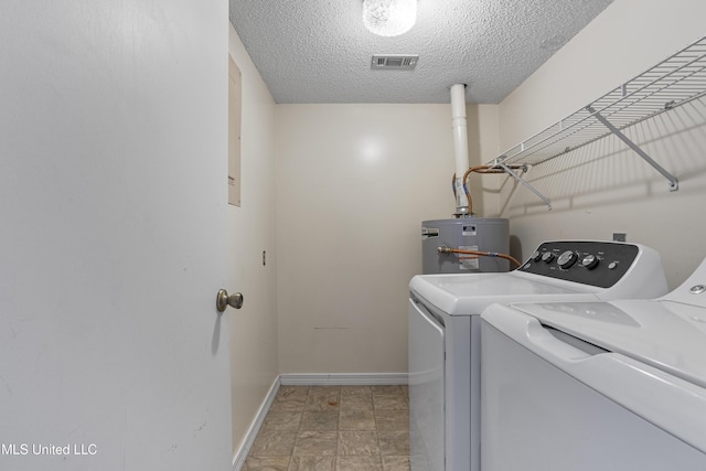 laundry room featuring water heater, washing machine and clothes dryer, and a textured ceiling