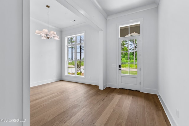 doorway with light hardwood / wood-style flooring, a chandelier, and crown molding