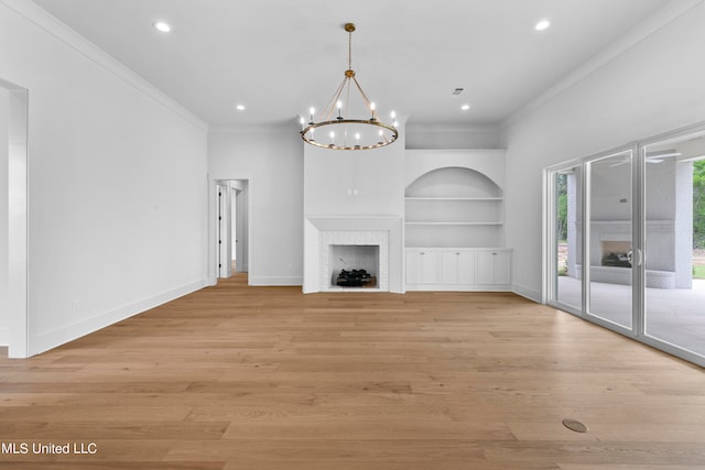 unfurnished living room with crown molding, a notable chandelier, light hardwood / wood-style flooring, and a fireplace