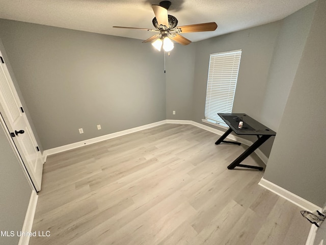 unfurnished room featuring ceiling fan, light wood-type flooring, and a textured ceiling