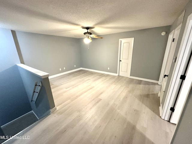 spare room with a textured ceiling, light hardwood / wood-style flooring, and ceiling fan