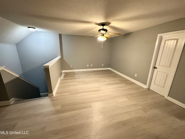 additional living space with ceiling fan, light wood-type flooring, a textured ceiling, and vaulted ceiling