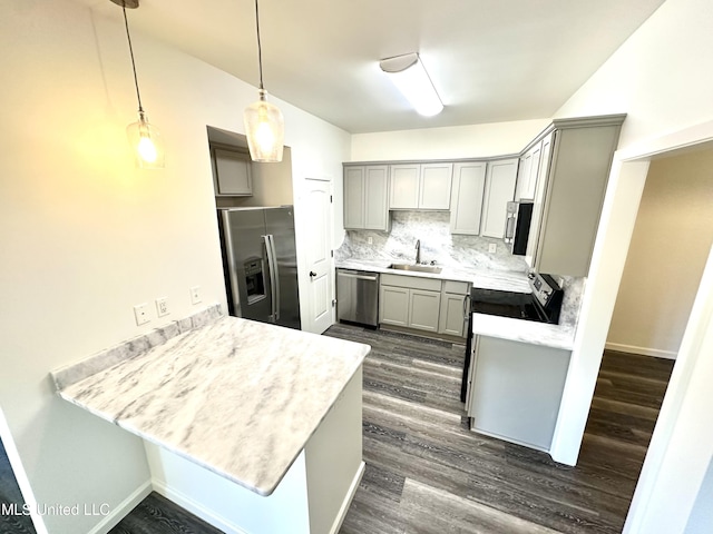 kitchen featuring kitchen peninsula, appliances with stainless steel finishes, backsplash, sink, and pendant lighting