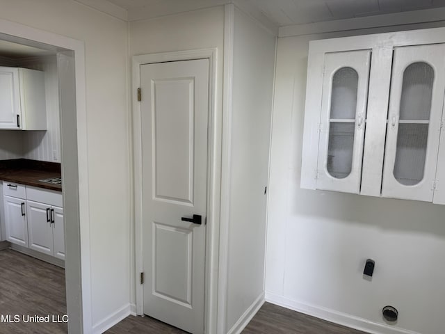 laundry area featuring baseboards and dark wood-type flooring
