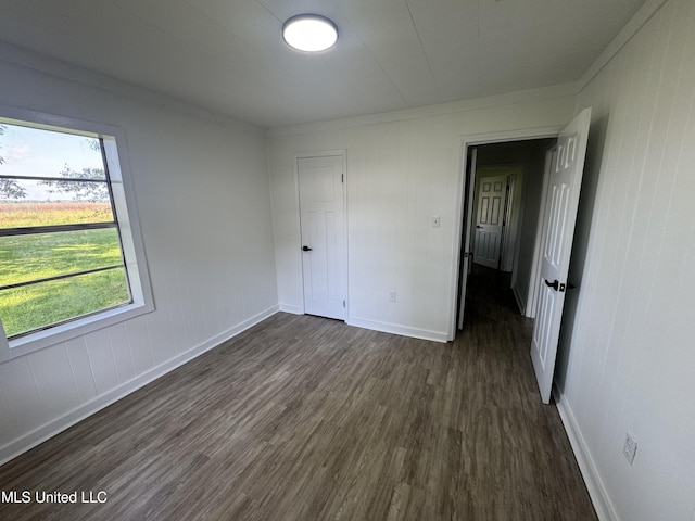 unfurnished bedroom with baseboards, a closet, and dark wood finished floors