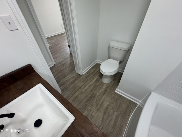 full bath featuring toilet, baseboards, a sink, and wood finished floors