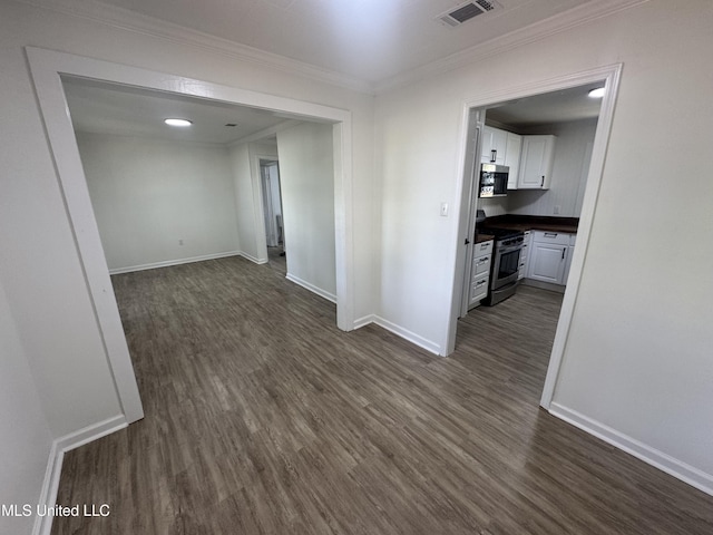 spare room featuring crown molding, baseboards, dark wood-style flooring, and visible vents
