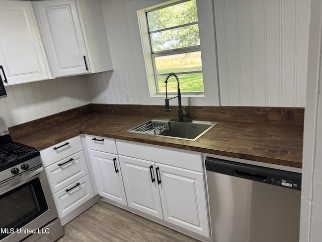 kitchen featuring white cabinets, appliances with stainless steel finishes, wooden counters, and a sink